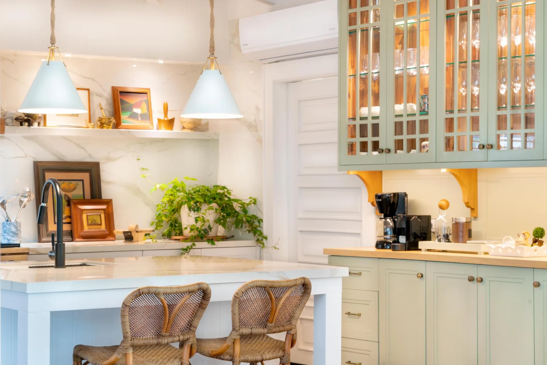 A bright kitchen with a counter, two stools, and glass-front cabinets.