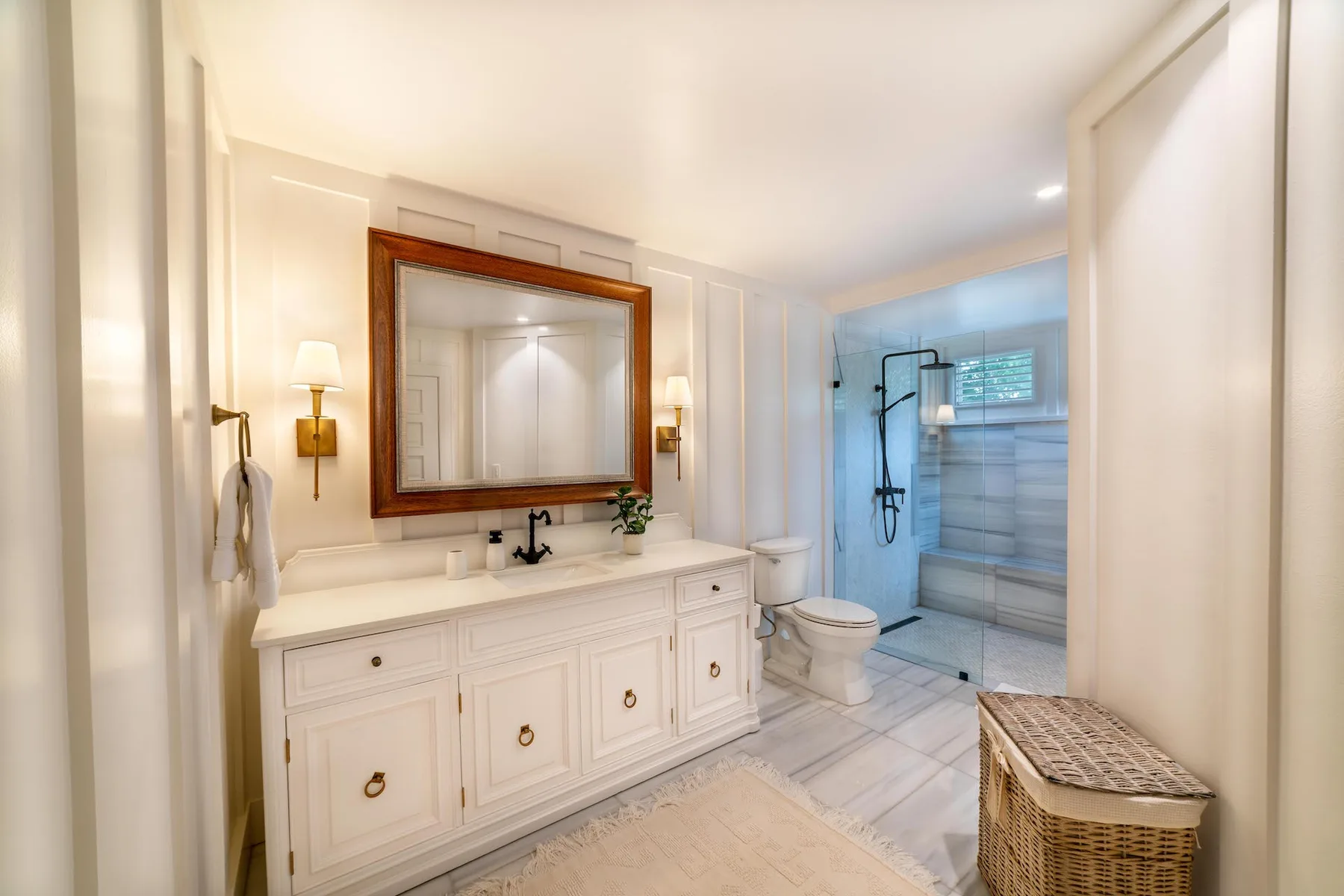 A bright bathroom with a long vanity, mirror, and glass shower.