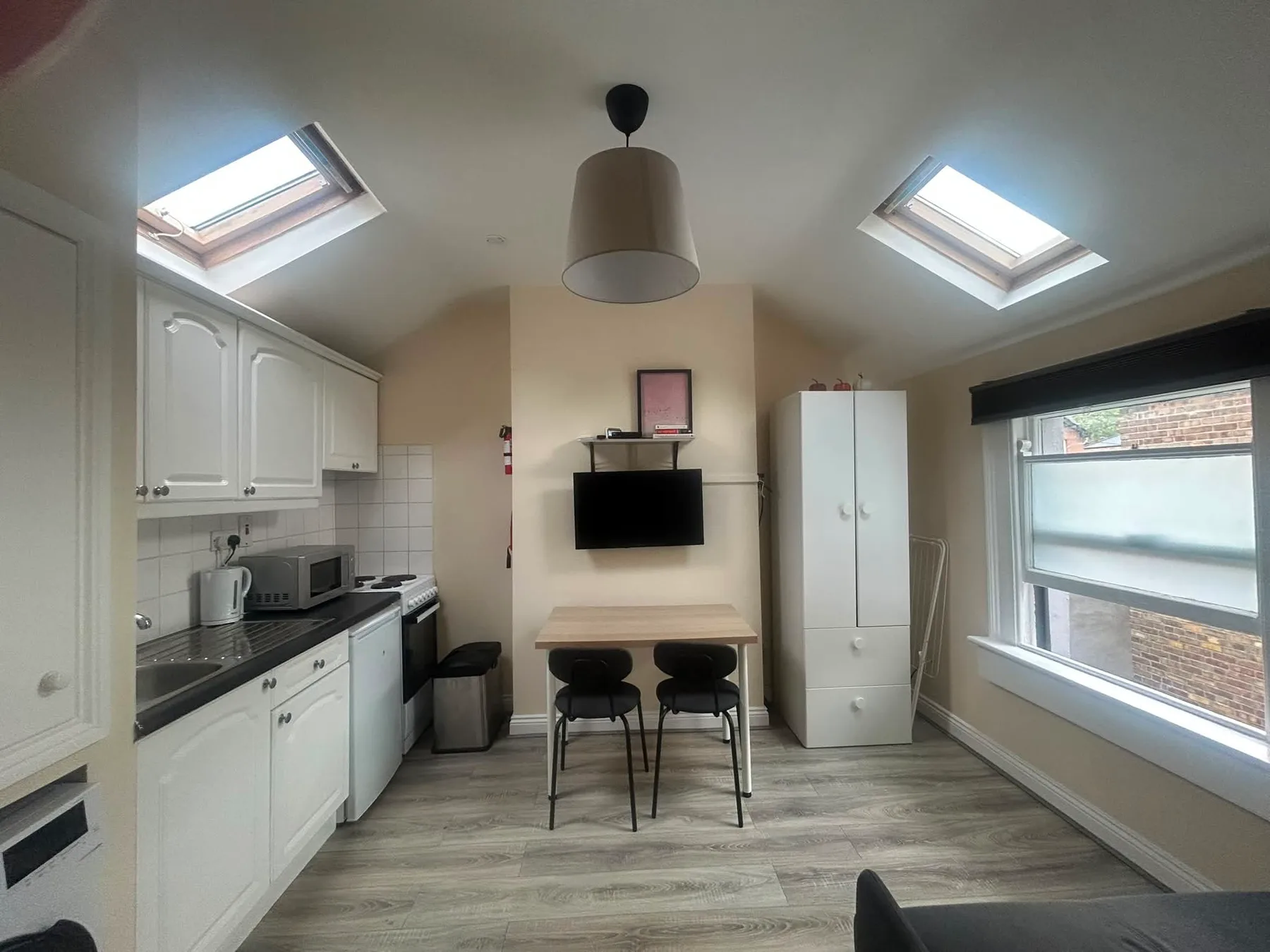 A bright kitchen with a dining table beneath two skylights.
