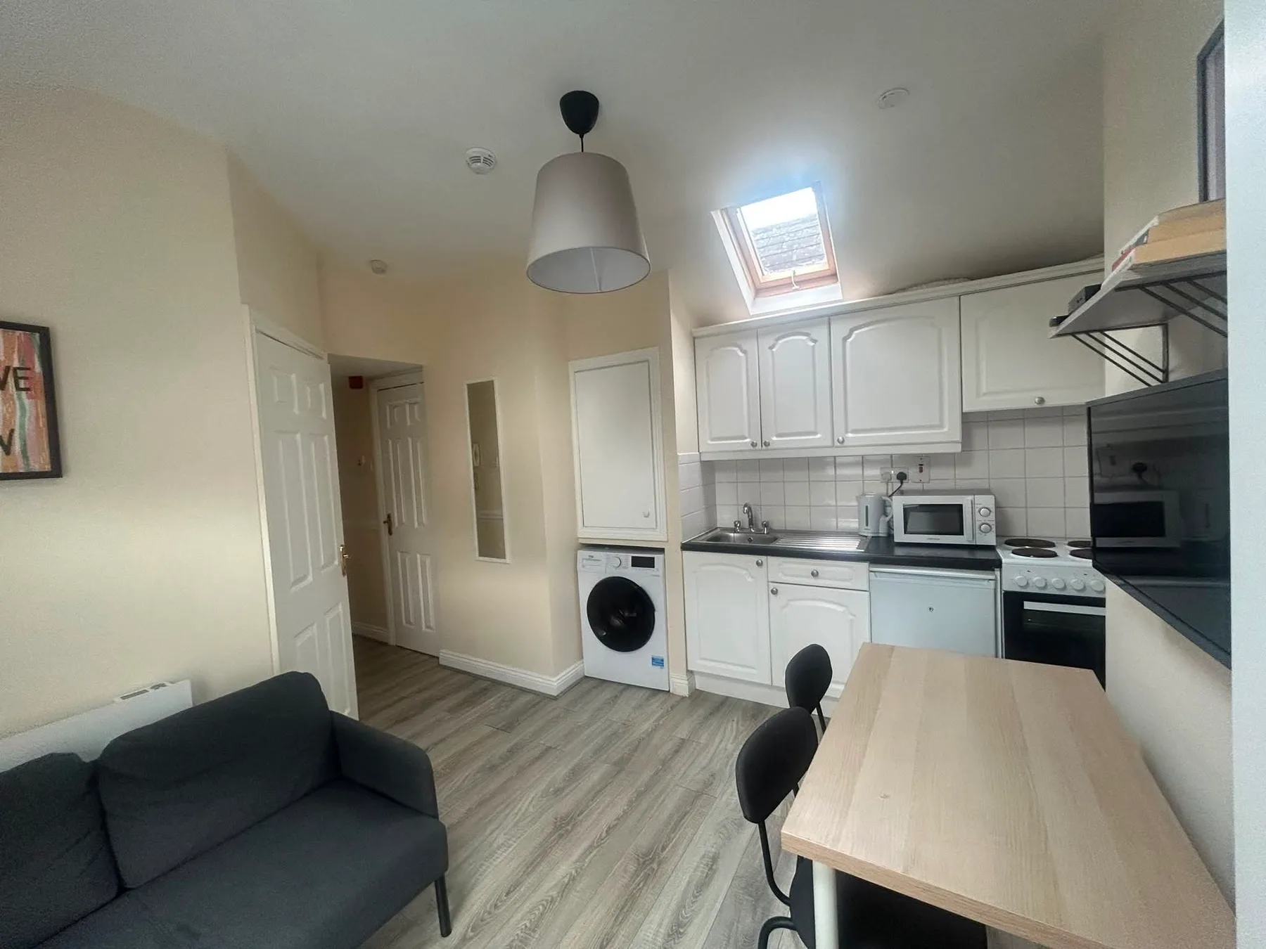A compact kitchen and dining area with white cabinets, appliances, and a table.