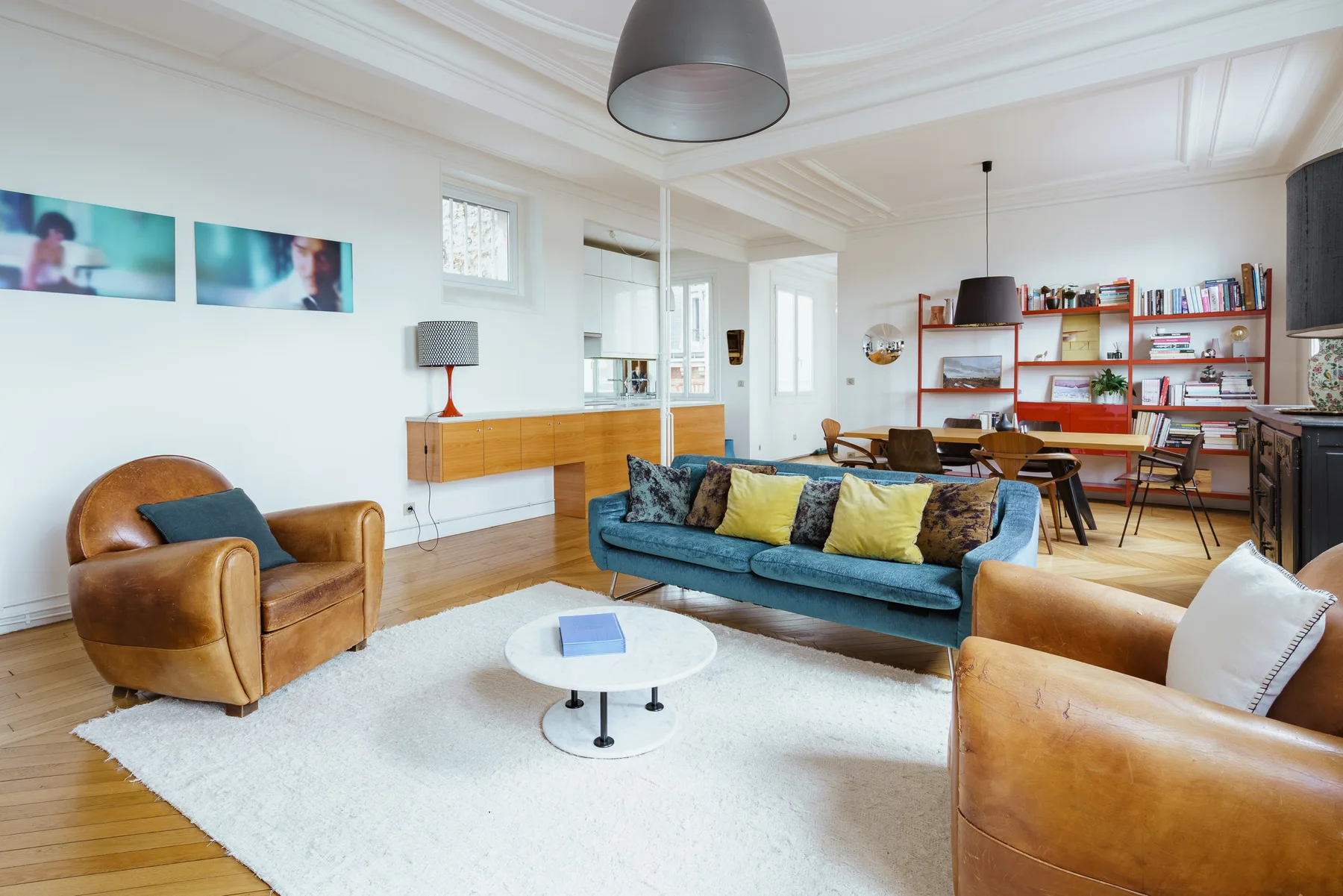 A bright living room with seating around a coffee table and a dining area beyond.