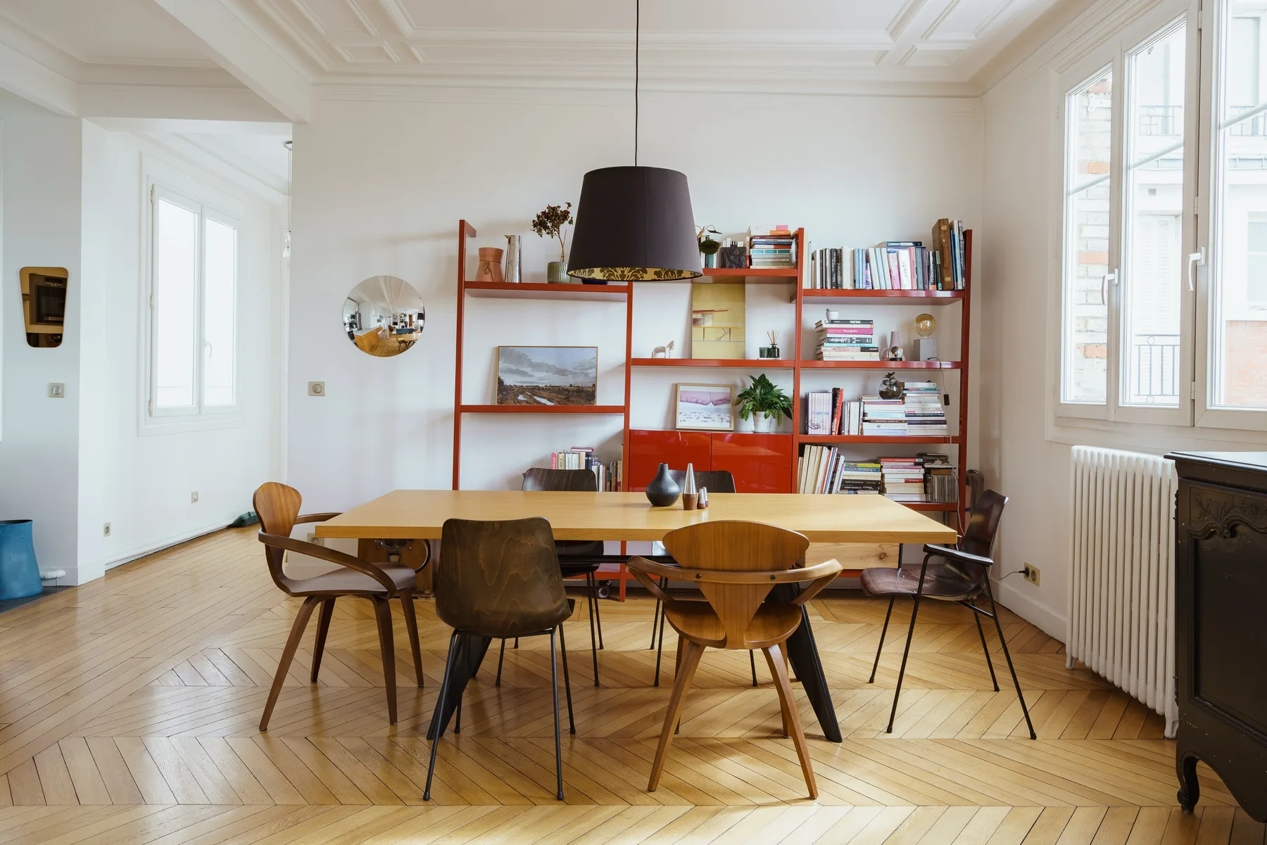 Un comedor luminoso con una mesa de madera, asientos y estanterías junto a la pared.