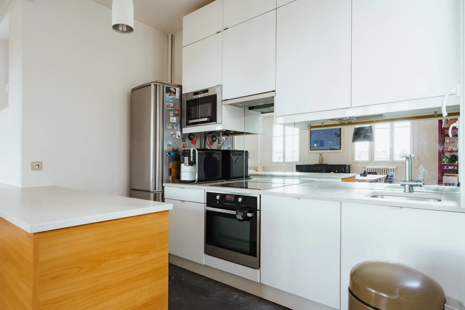 A bright modern kitchen with white cabinets, a countertop, and built-in appliances.