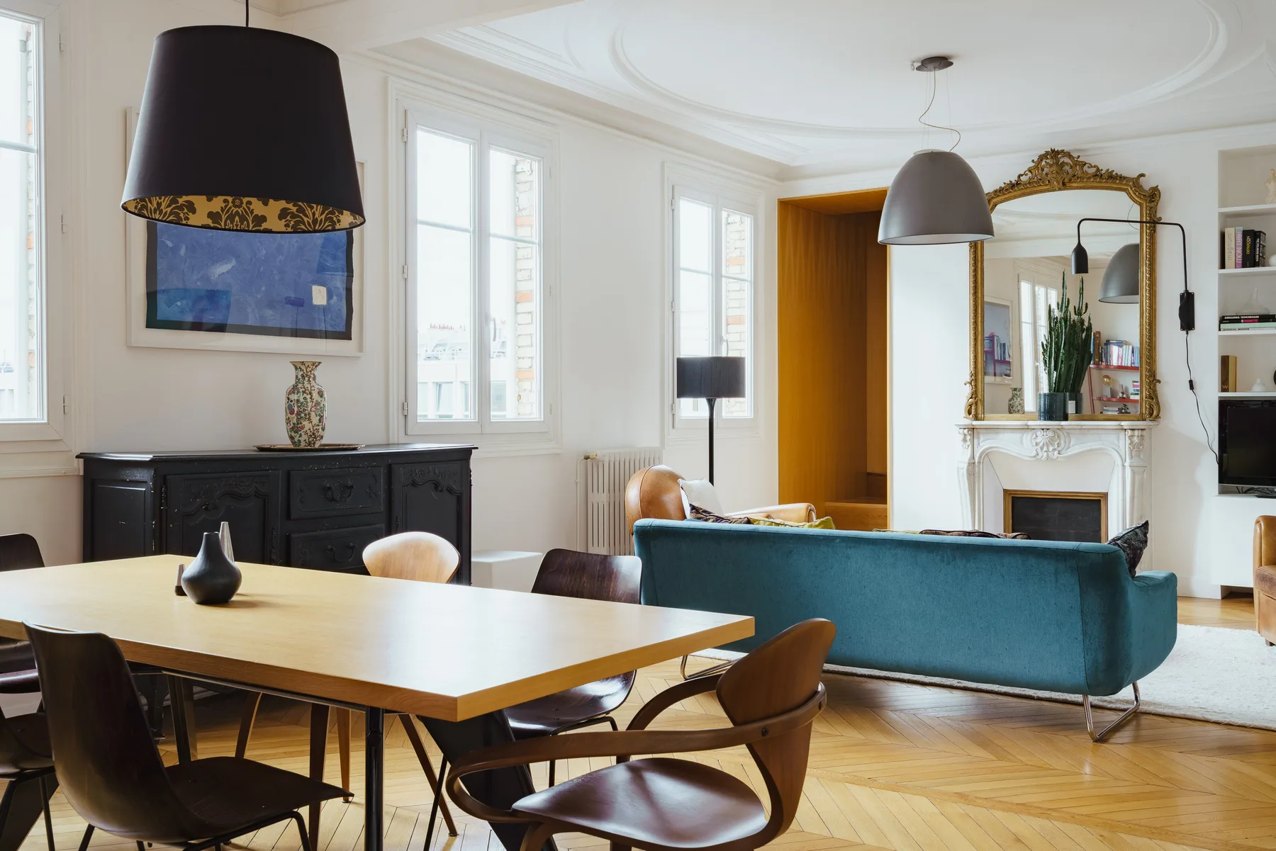 A bright living and dining room with a large table and blue seating.