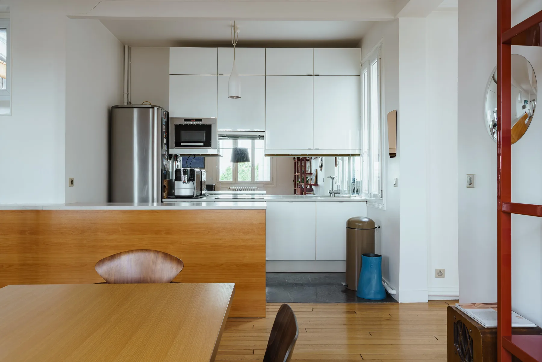A bright kitchen with white cabinets, stainless steel appliances, and a wooden dining table.