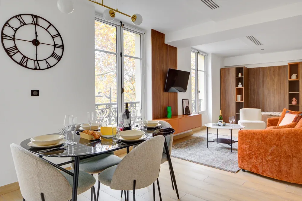 Comedor y sala de estar con una mesa puesta, asientos naranjas y muebles de madera.
