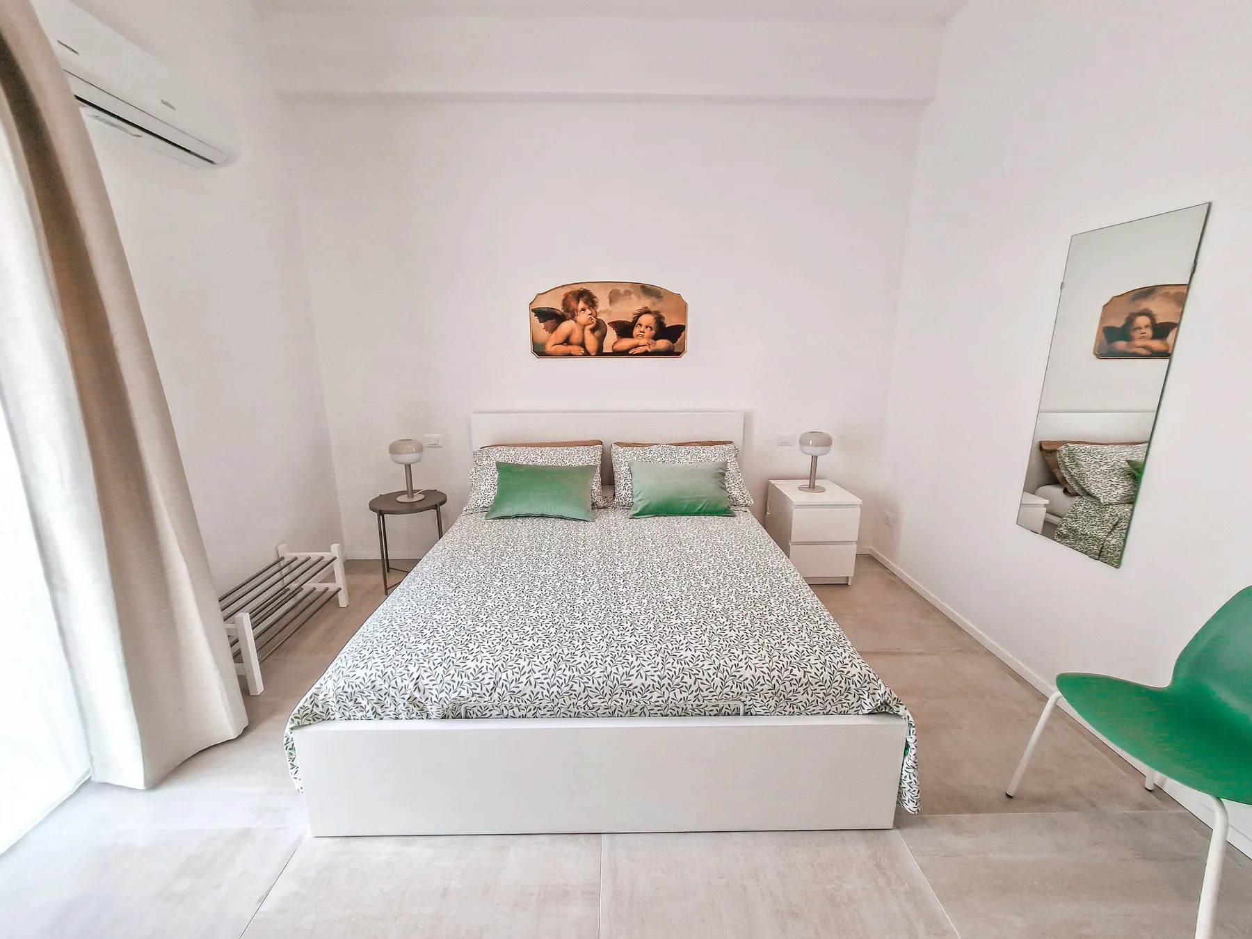 Un dormitorio con una cama doble, mesas de noche y una silla verde.