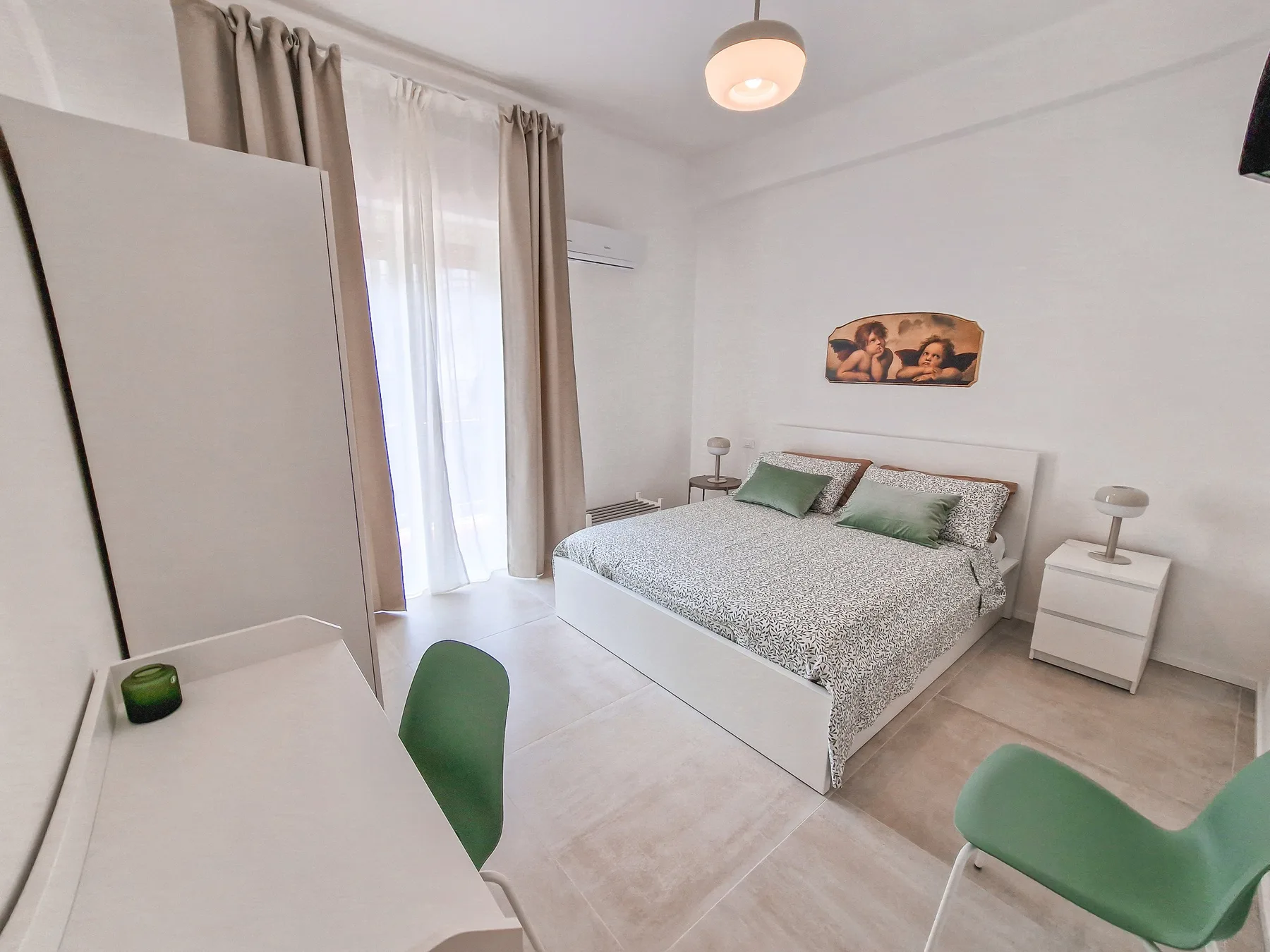 A bright bedroom with a double bed, bedside tables, and a desk.