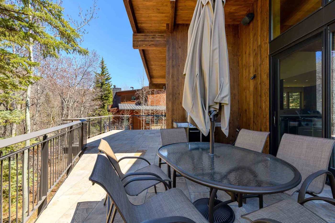 Un patio exterior con asientos y una mesa junto a una pared de madera.