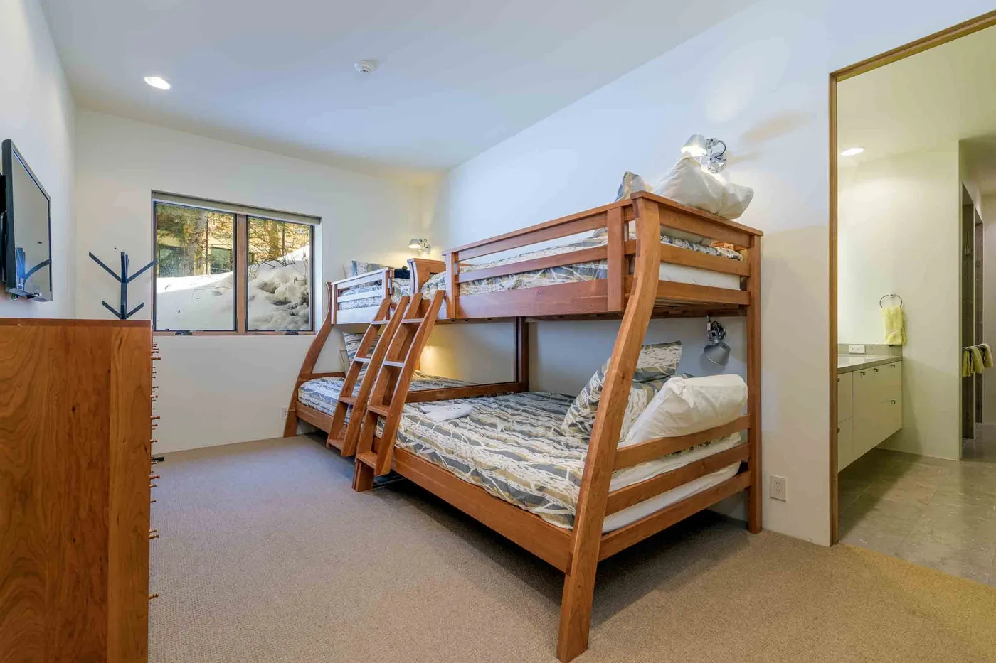 Una litera ocupa un dormitorio luminoso, con una ventana y una puerta abierta.