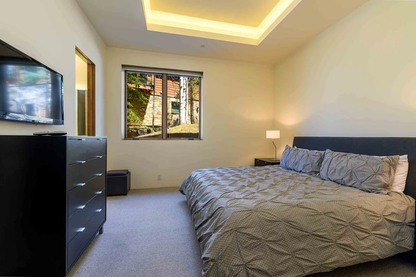 Un dormitorio con una cama grande, una lámpara de noche y una ventana.