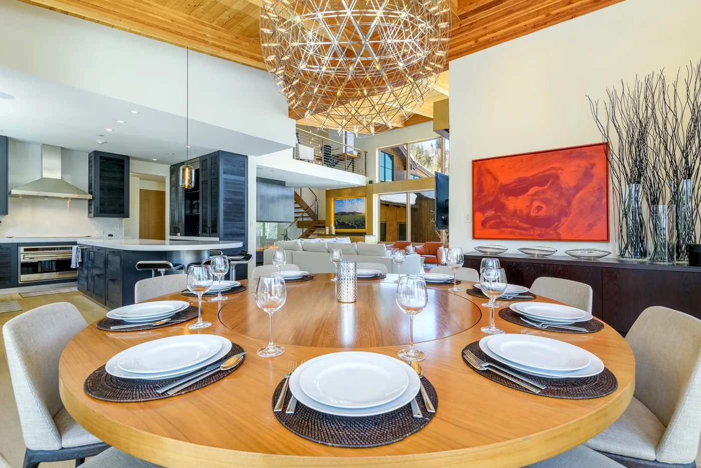 Un comedor con una mesa redonda preparada con platos y copas.