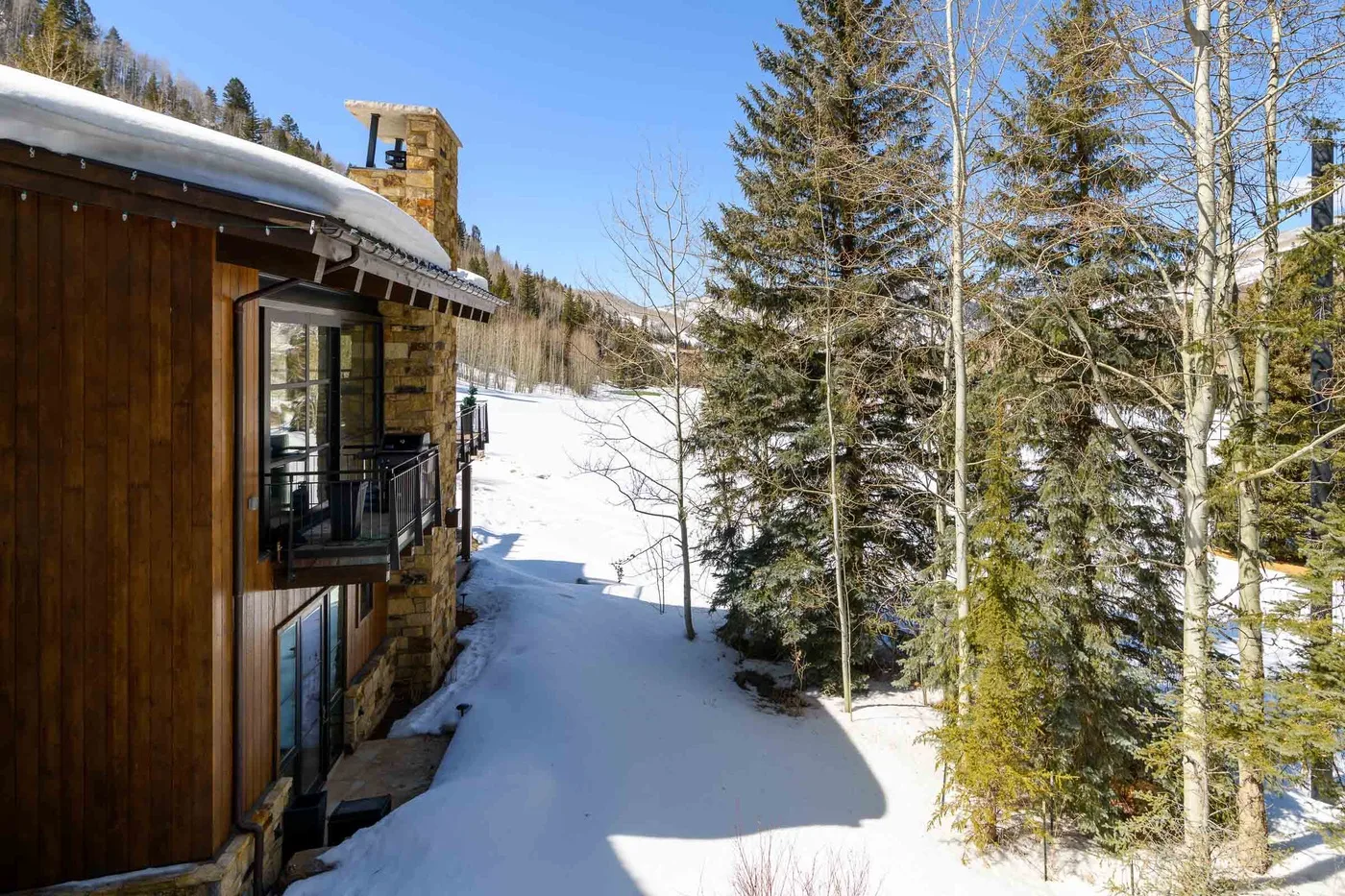 Un área exterior cubierta de nieve junto a un edificio de madera y árboles de hoja perenne.