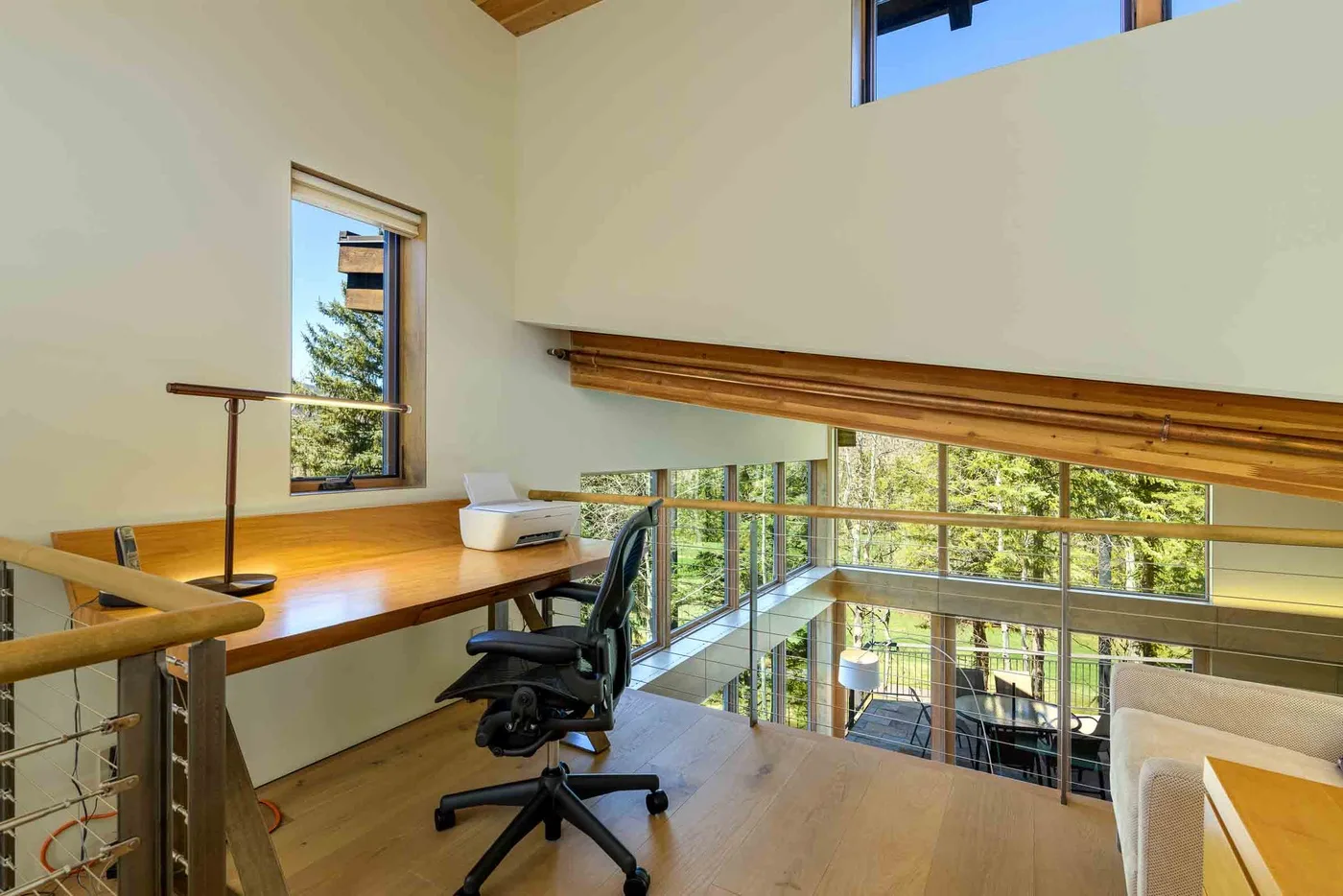 Un espacio de trabajo tipo loft con escritorio y silla de oficina junto a grandes ventanas.
