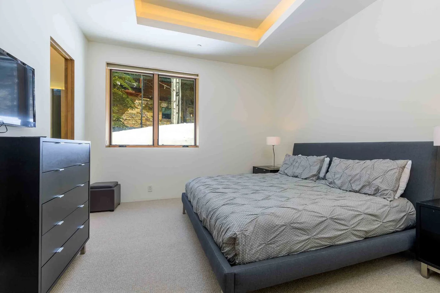Un dormitorio con una cama grande, una ventana y un televisor.