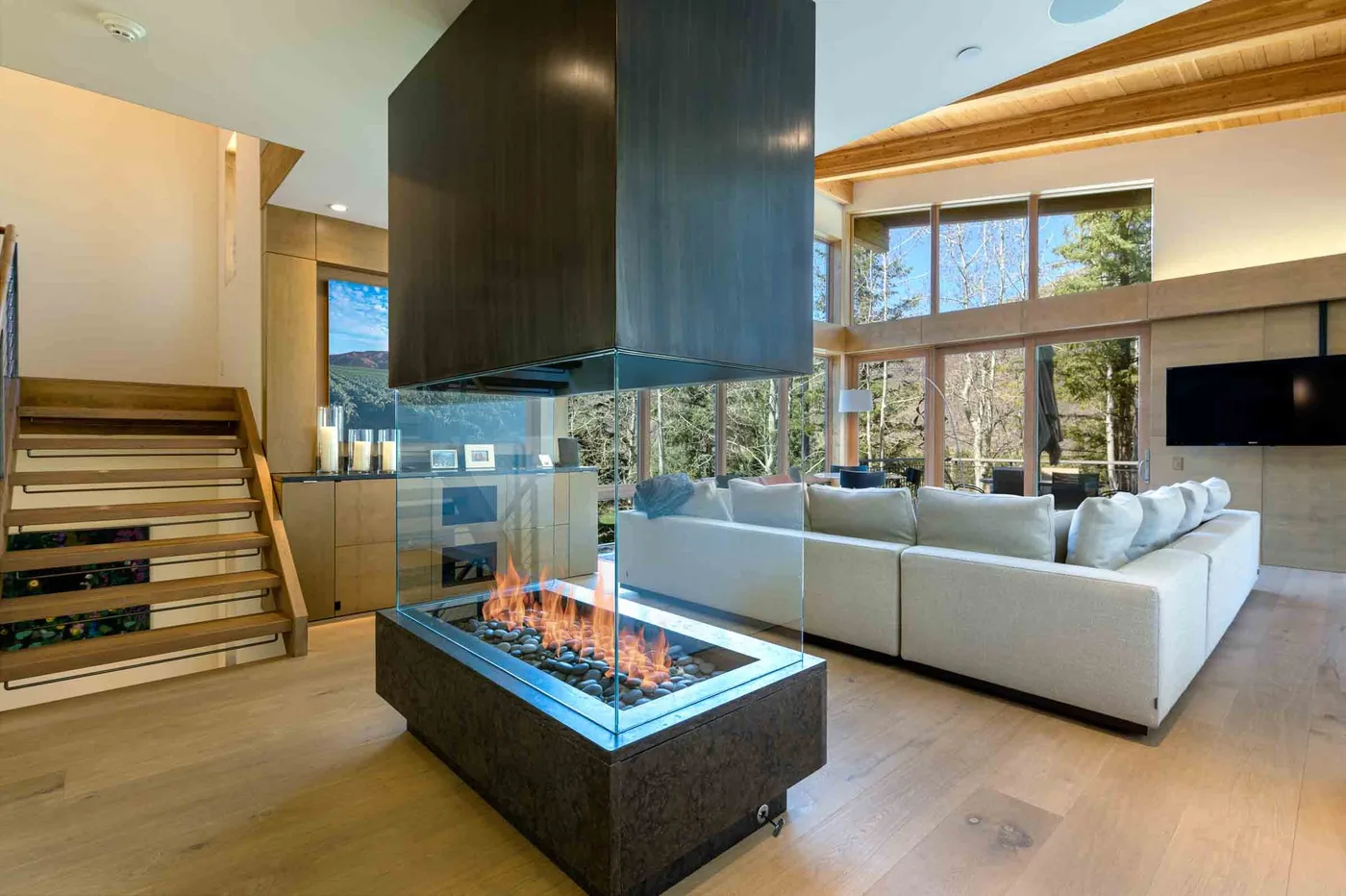 Una sala luminosa con una zona de asientos y una chimenea central de cristal.
