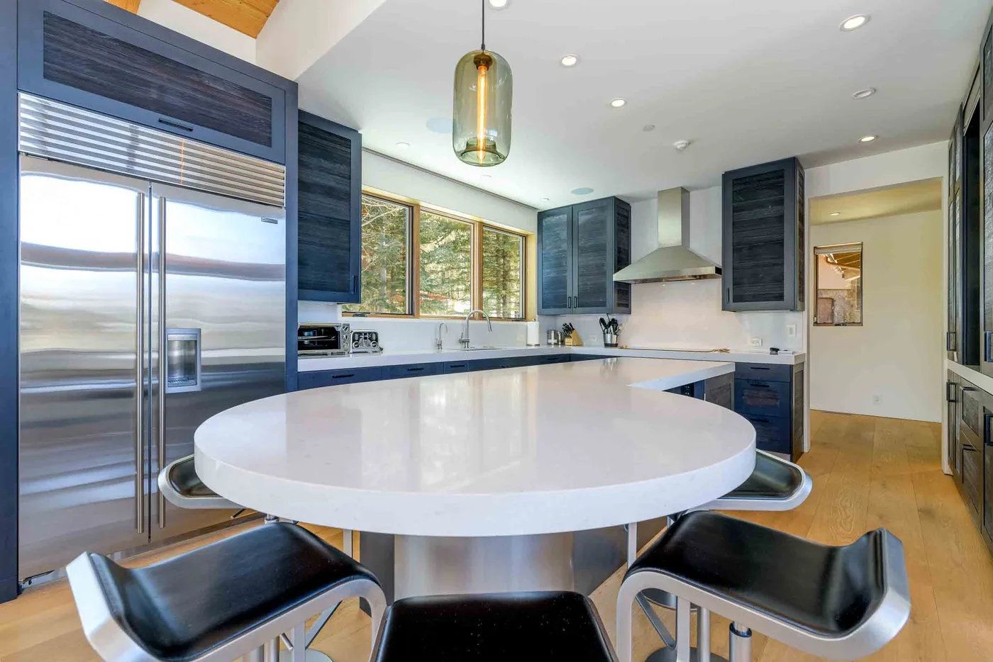 Una cocina moderna con gabinetes oscuros, electrodomésticos de acero inoxidable y una gran isla blanca.