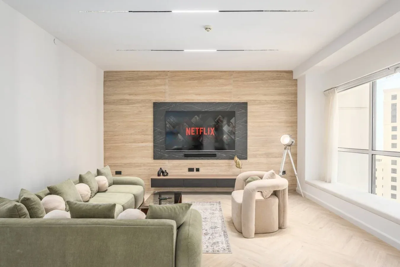 Una luminosa sala de estar tiene asientos alrededor de un televisor en la pared.
