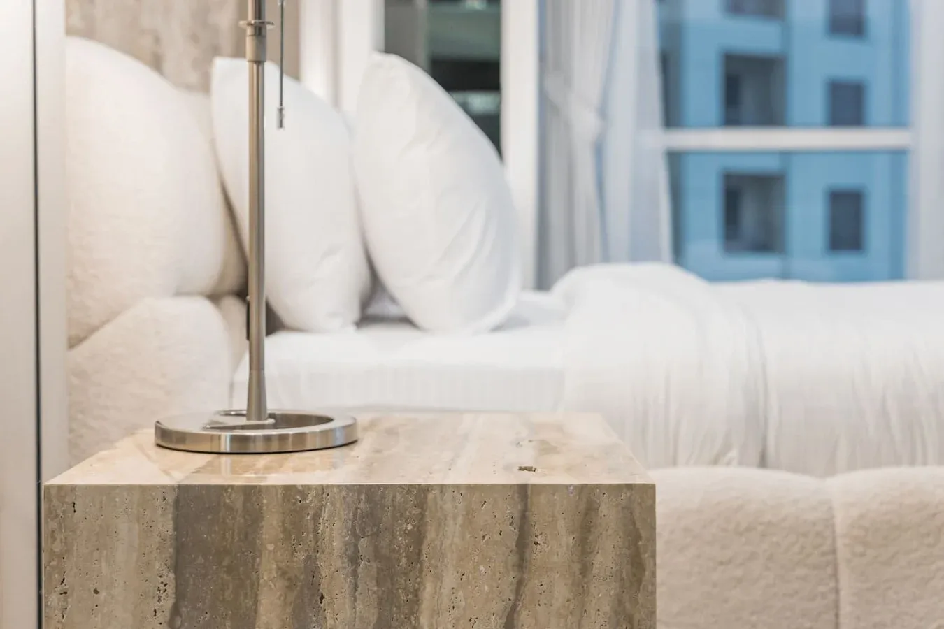 Una zona de descanso en un dormitorio con asientos blancos junto a una mesa de piedra.