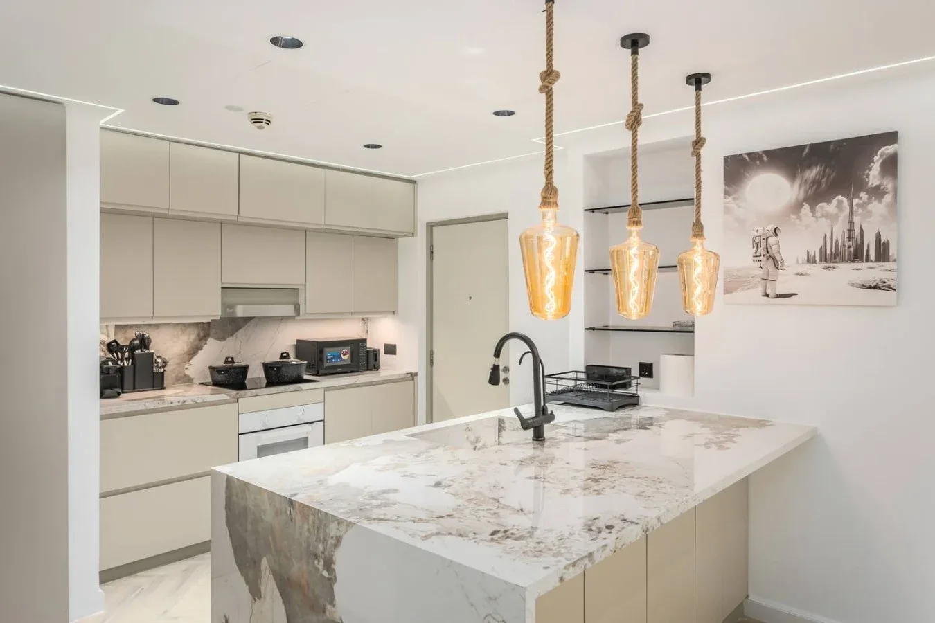 Una cocina moderna y luminosa con una isla grande y lámparas colgantes.