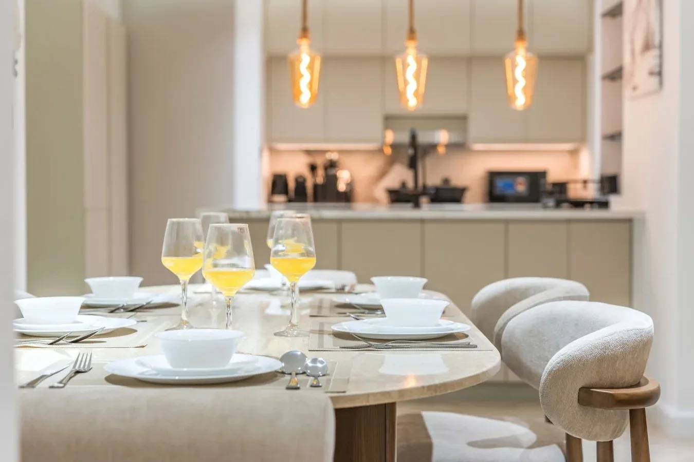 Comedor con una mesa puesta en primer plano y una cocina al fondo.