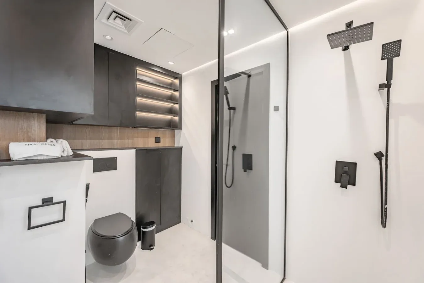 Un baño moderno con una ducha de vidrio y un inodoro junto al tocador.