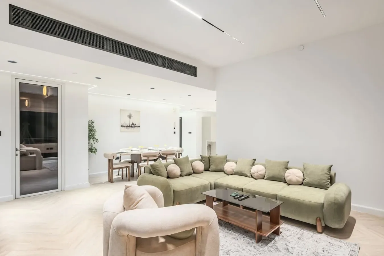 Una sala luminosa con un sofá seccional verde y una mesa de centro.