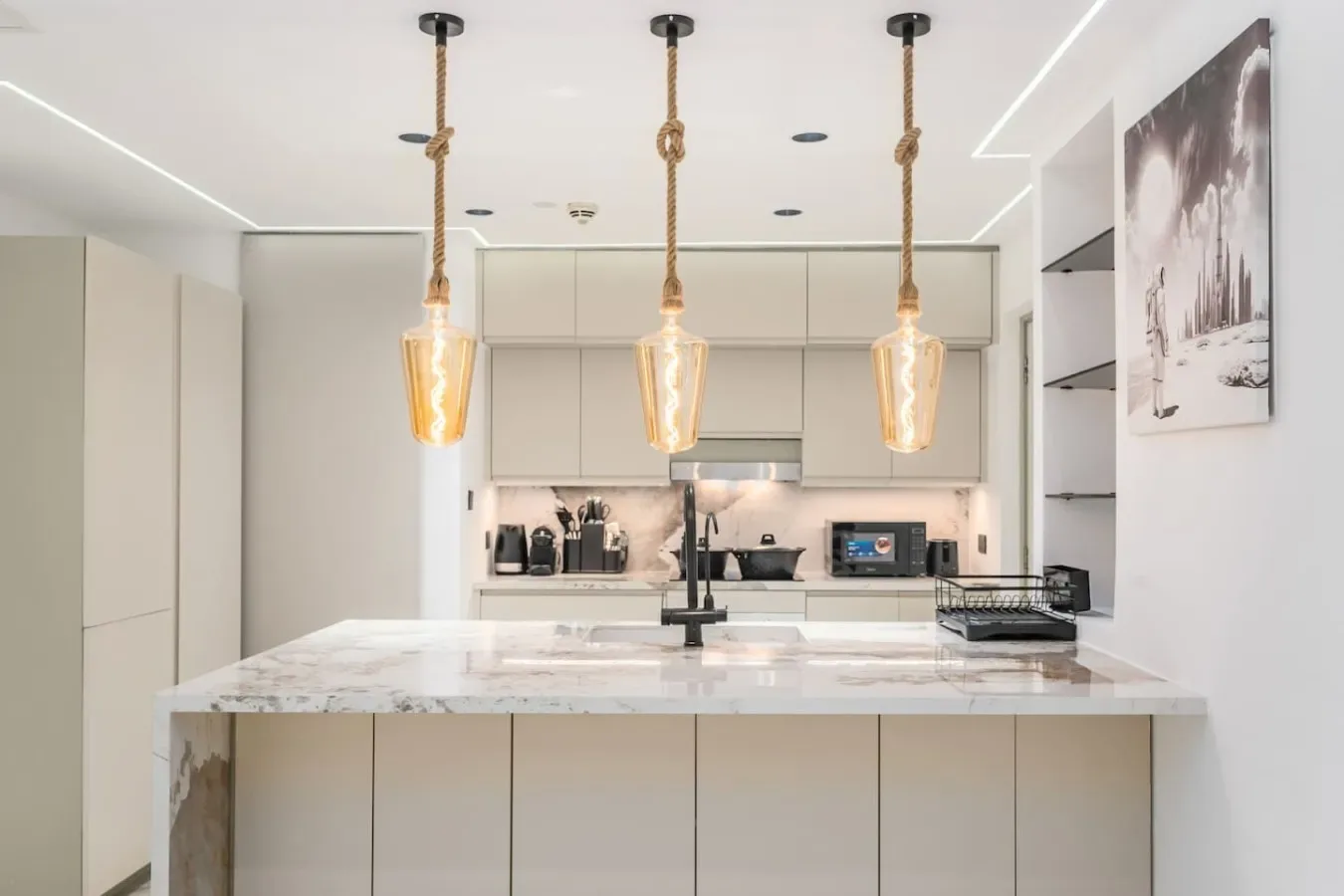 Una cocina moderna y luminosa con una isla grande y lámparas colgantes.