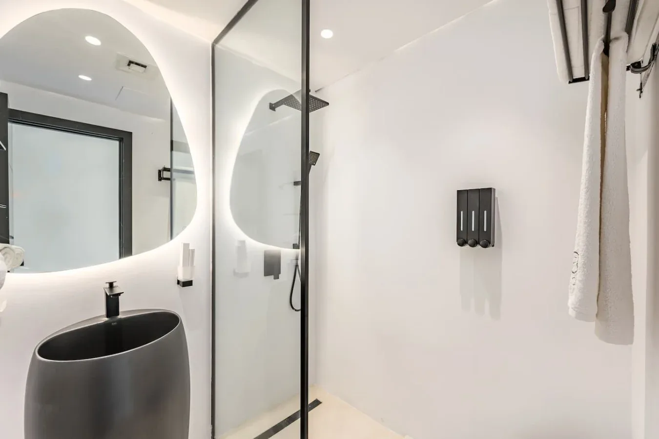Un baño moderno con un lavabo oscuro y una mampara de ducha de vidrio.
