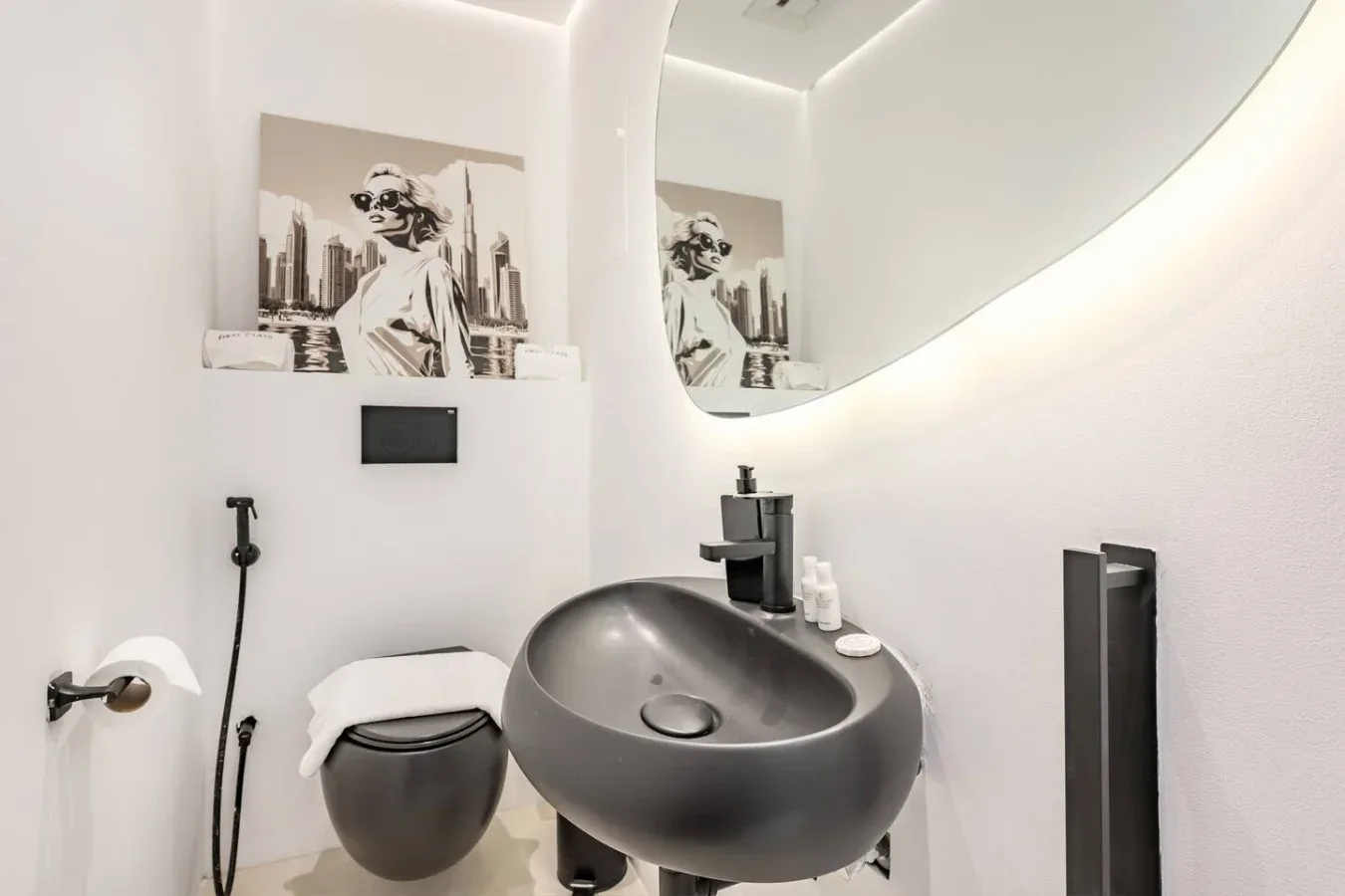 Un baño moderno con un lavabo oscuro sobre encimera y un inodoro suspendido.