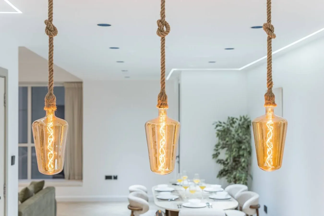 Un comedor luminoso con una mesa y tres lámparas colgantes.