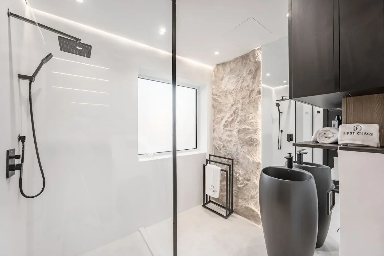 Un baño moderno con ducha a ras de suelo y lavabo de recipiente oscuro.