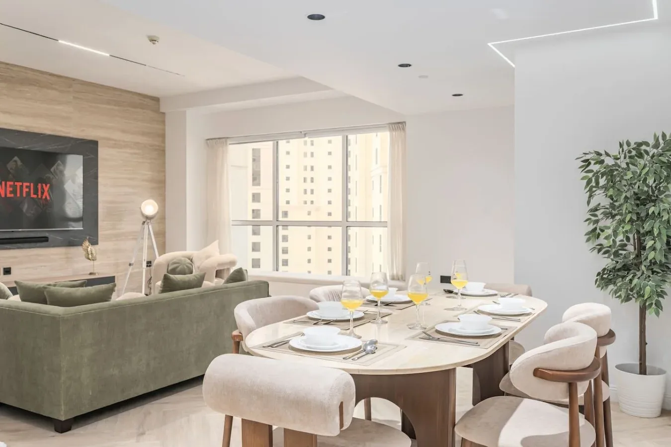 Una luminosa zona de comedor y sala de estar con una mesa grande junto a las ventanas.