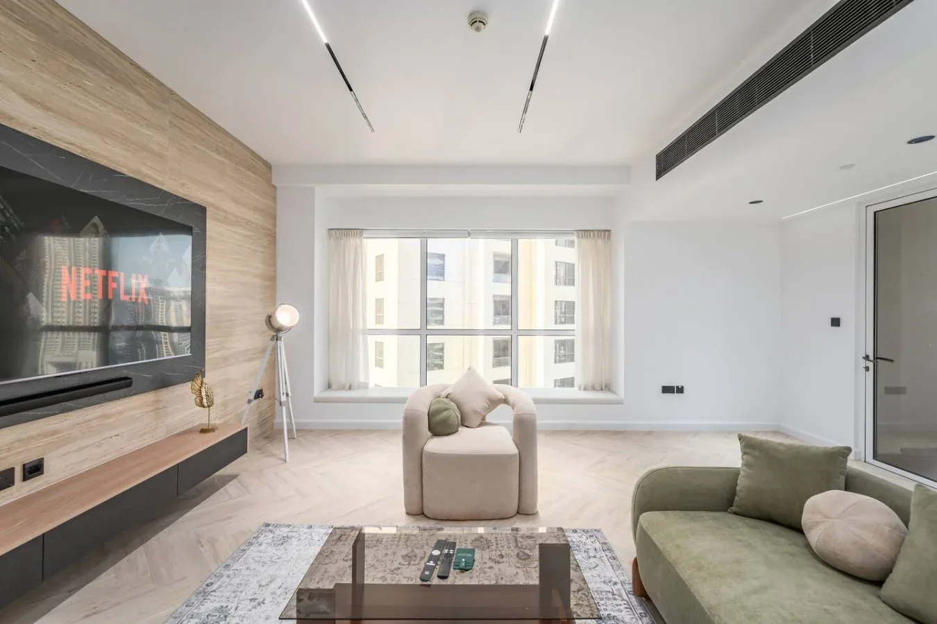 Una sala luminosa con televisor, mesa de centro y asientos junto a una ventana grande.