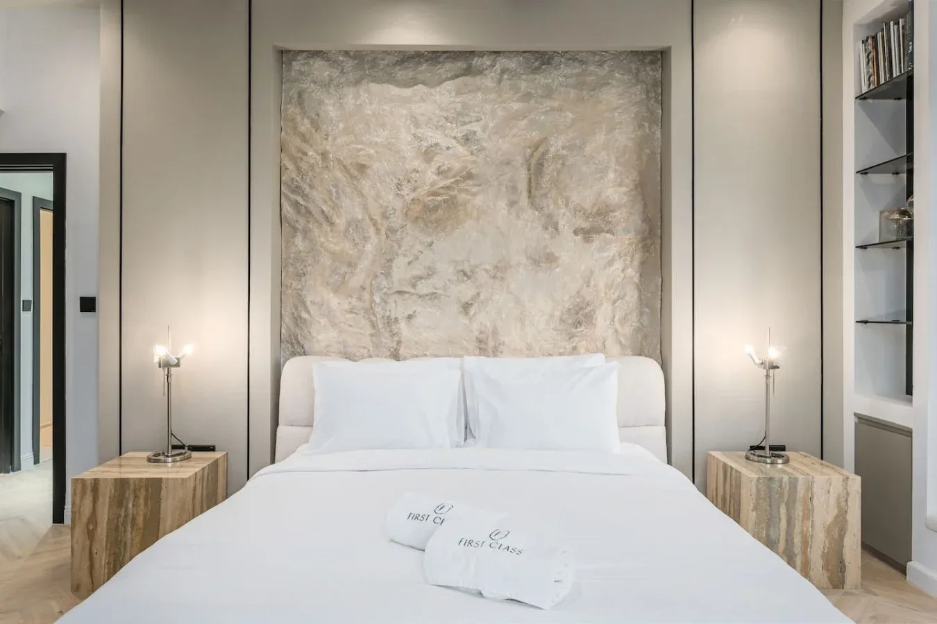Un dormitorio con una cama bien tendida y arte abstracto en la pared.