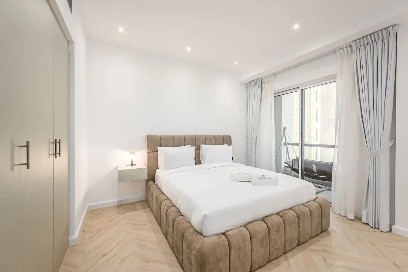 Un dormitorio luminoso con una cama grande junto a una ventana con cortinas.
