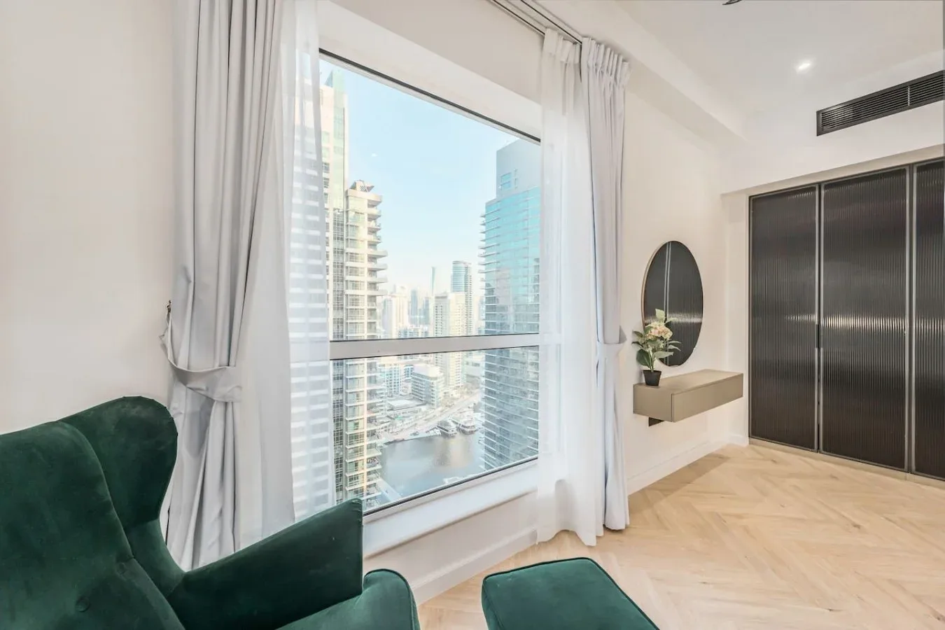 Un dormitorio luminoso con una gran ventana que da a edificios de la ciudad.