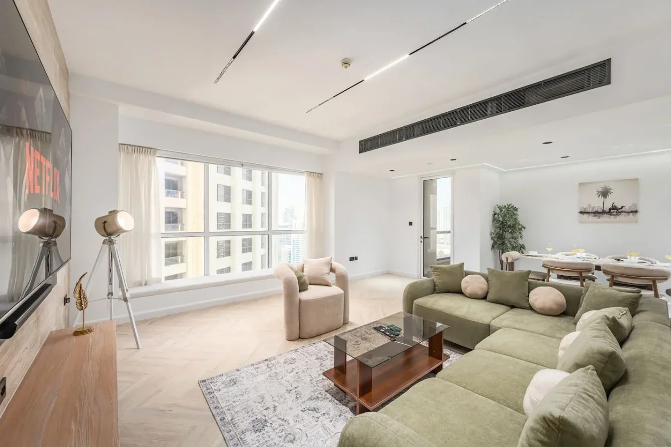 Una sala luminosa con asientos claros, una mesa de centro y grandes ventanas.