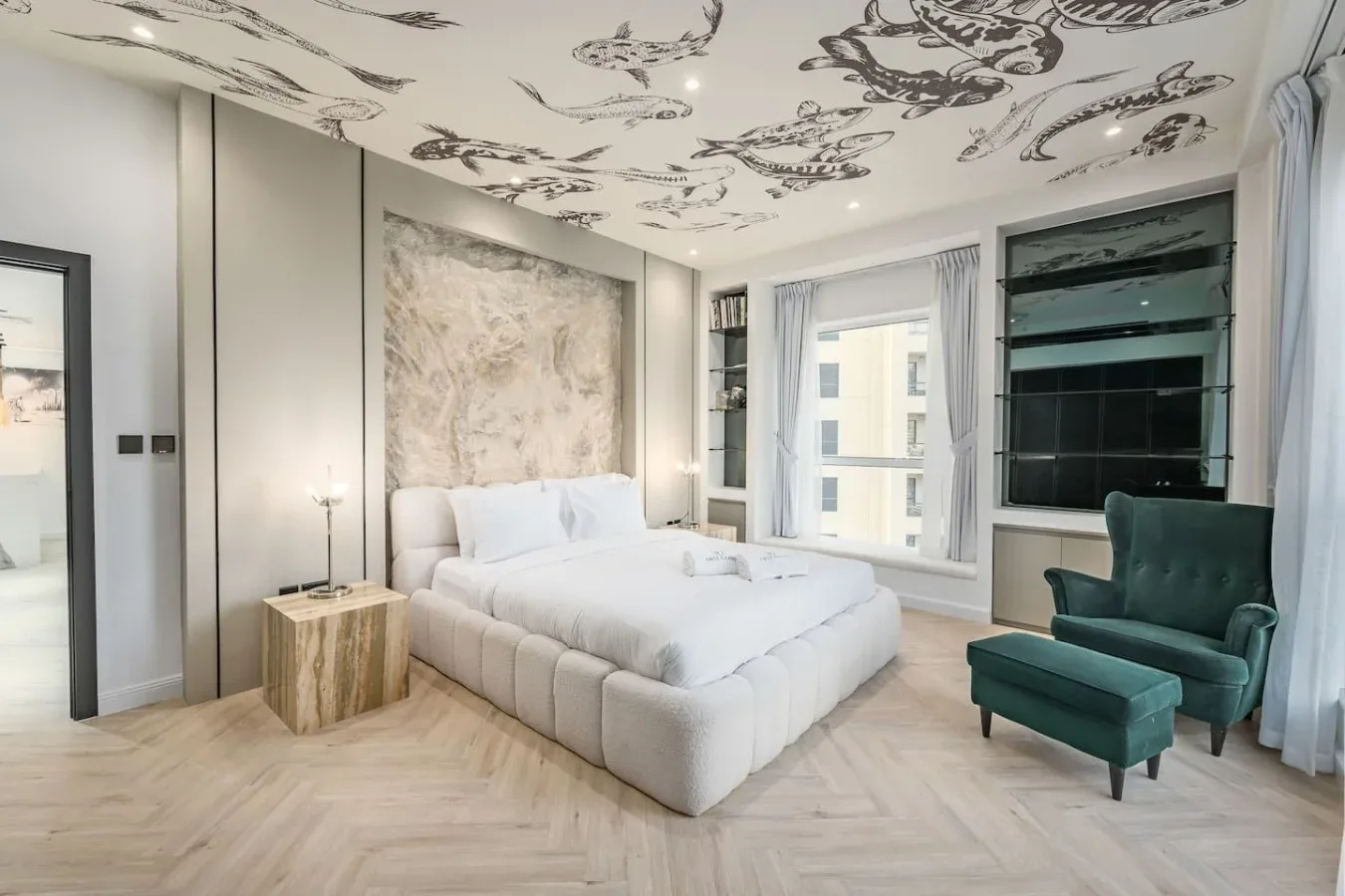 Un dormitorio con una cama, un sillón verde y ventanas grandes.