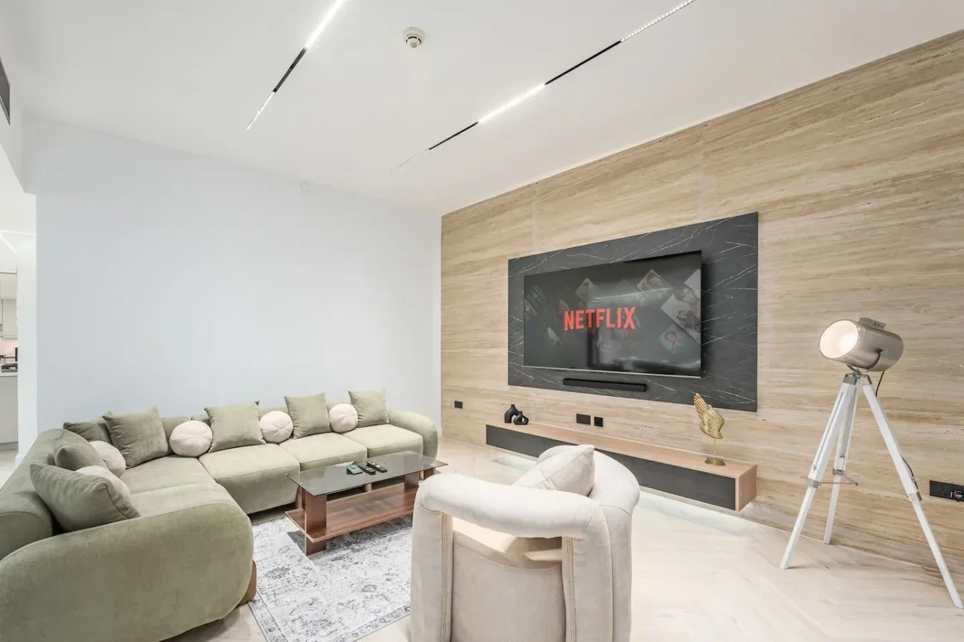 Una sala de estar moderna con un sofá seccional grande frente a un televisor montado en la pared.