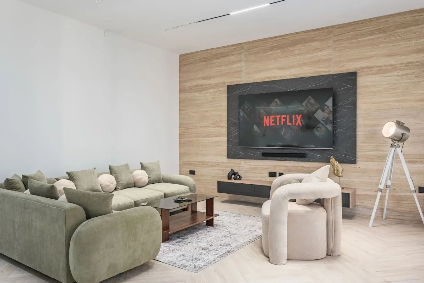 Una sala de estar con una amplia zona de asientos frente a un televisor montado en la pared.