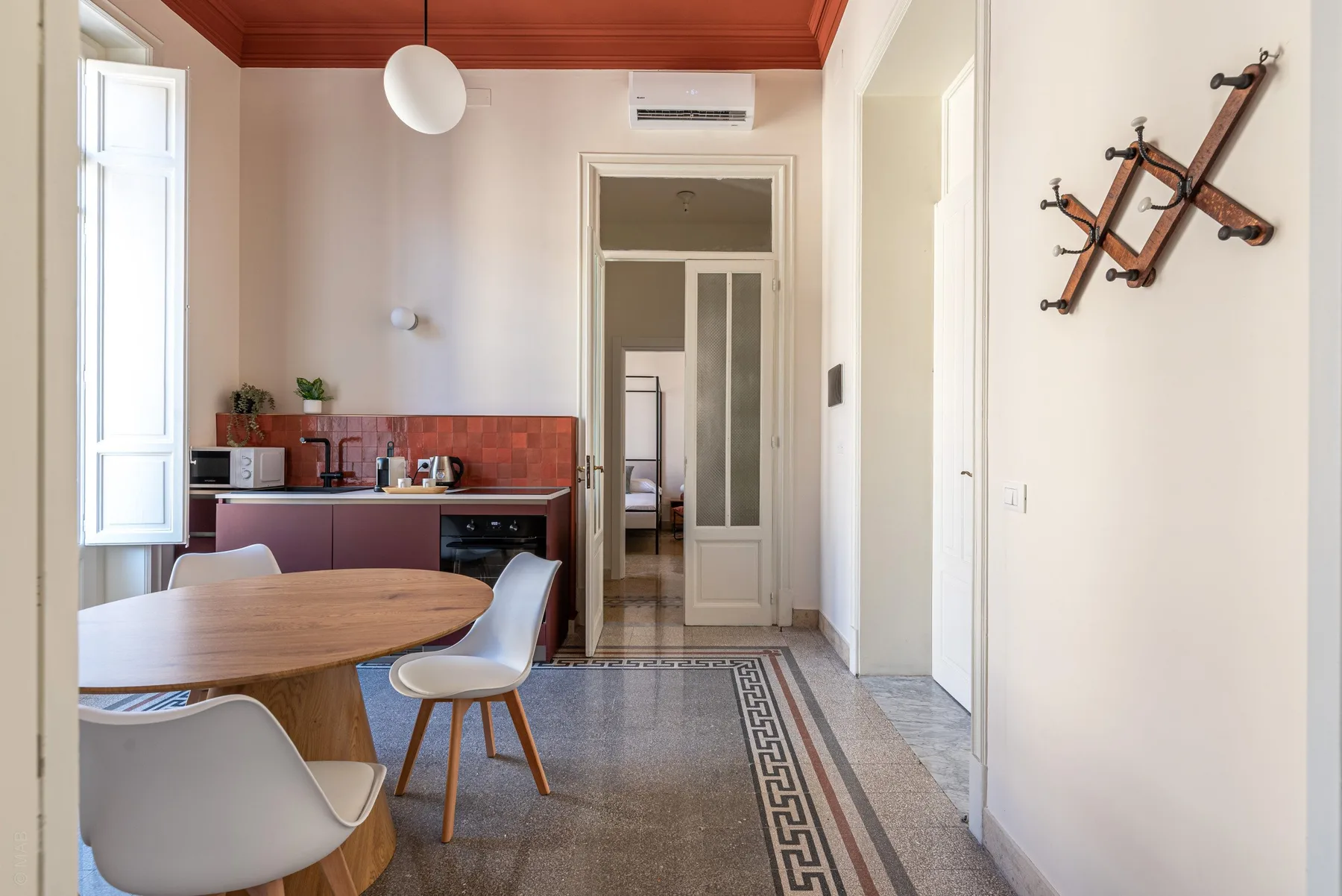 A dining area with a round table beside a compact kitchen.