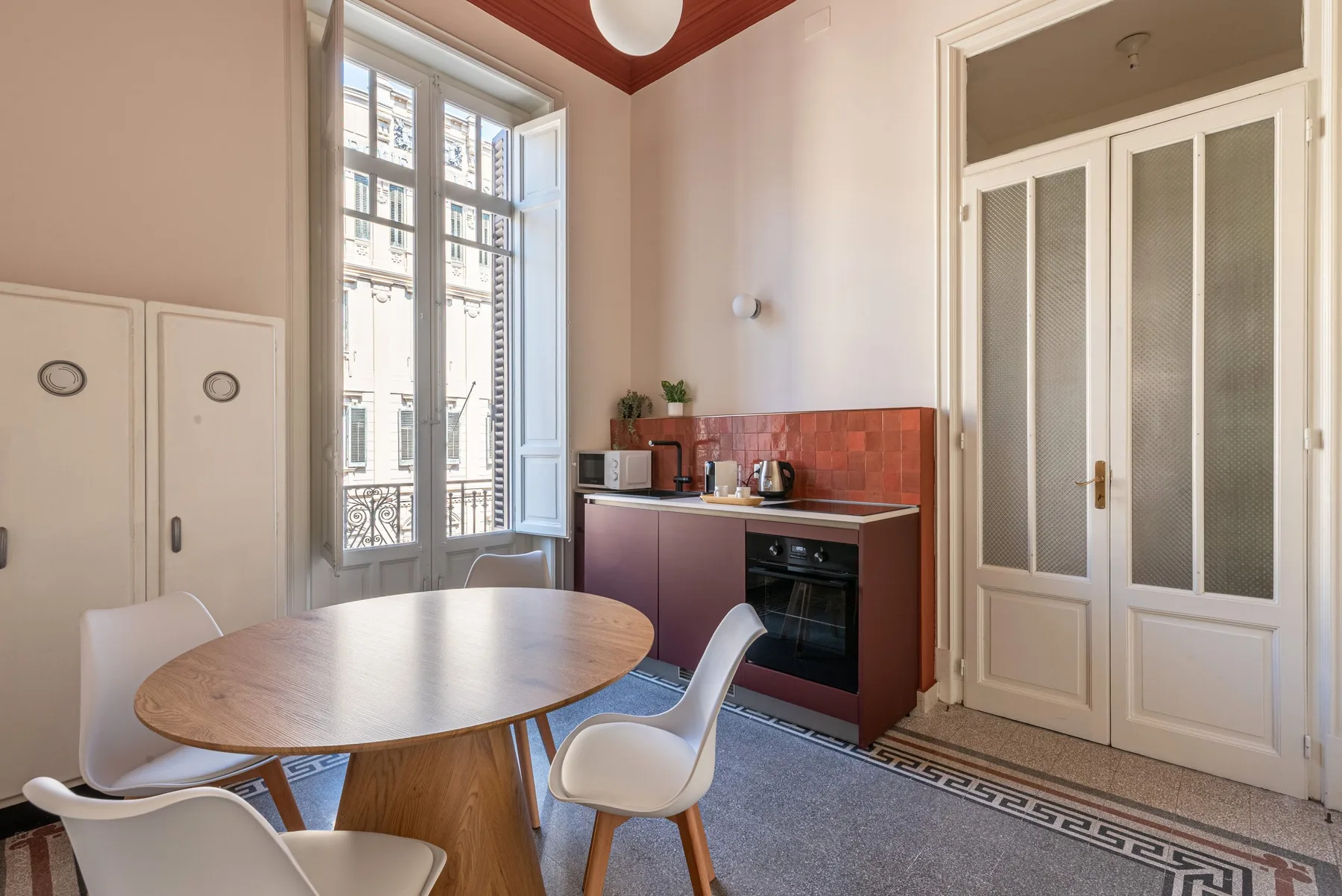 A dining area with a wooden table beside a compact kitchen counter.