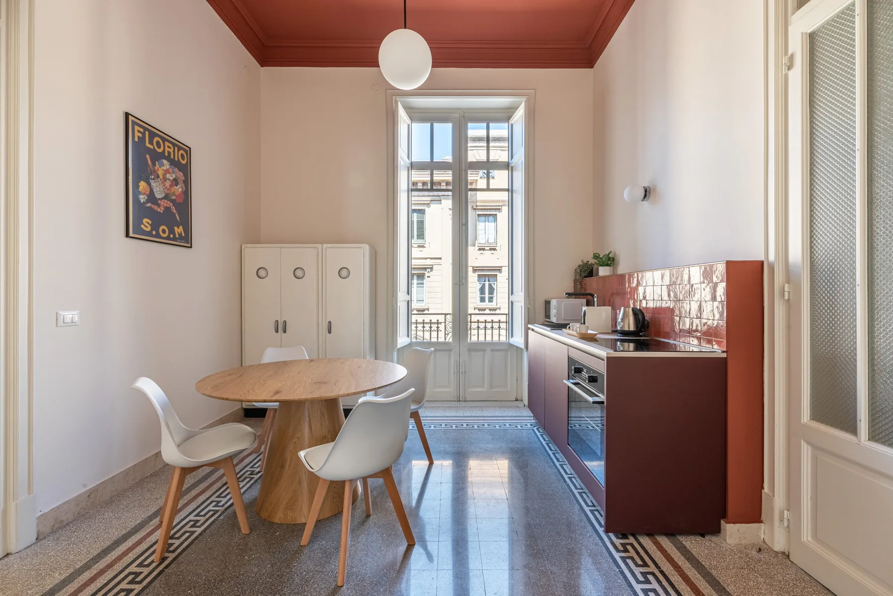 A dining area and kitchen with a round table beside a balcony door.