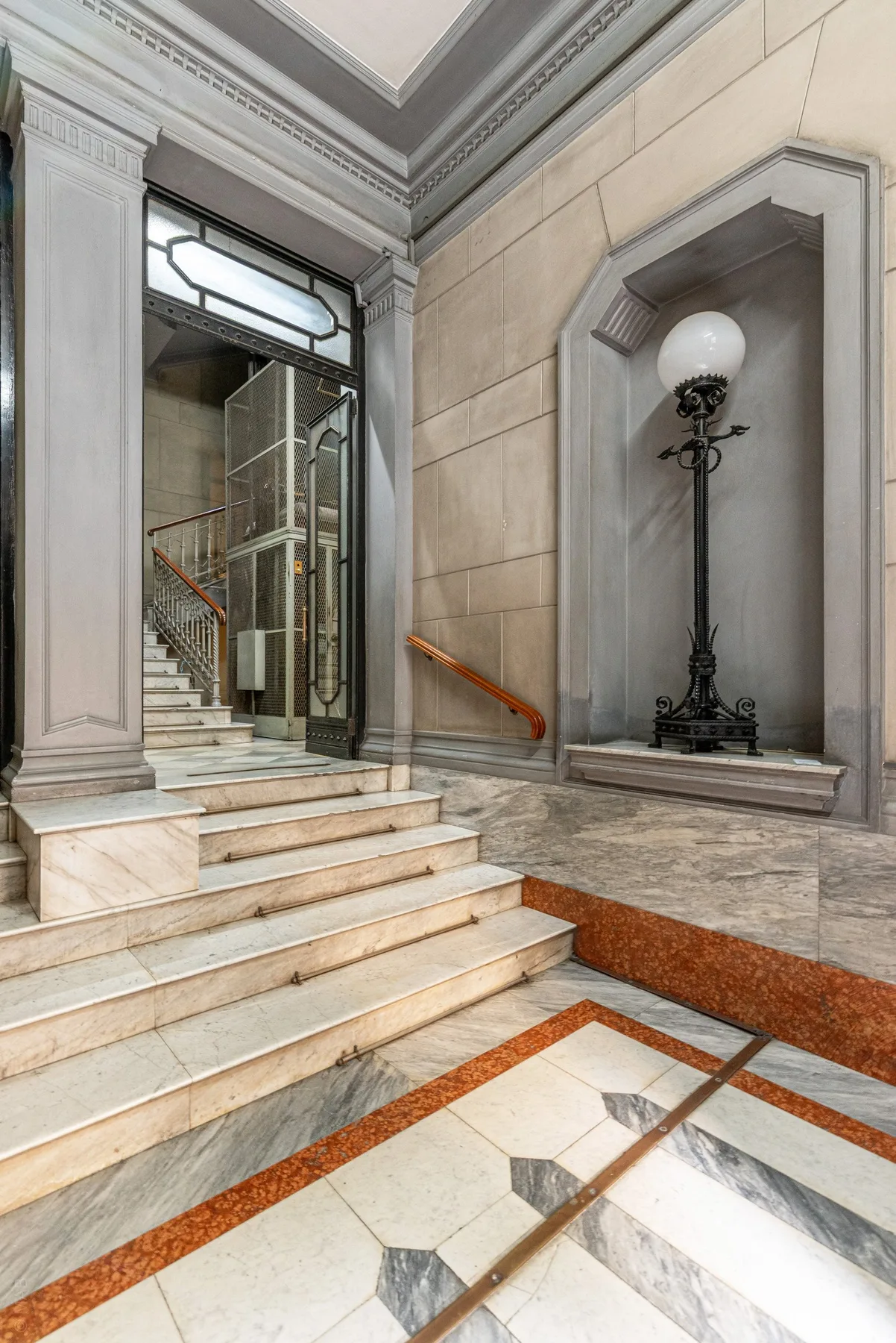 A grand stone interior with marble steps, a decorative lamp, and a patterned floor.