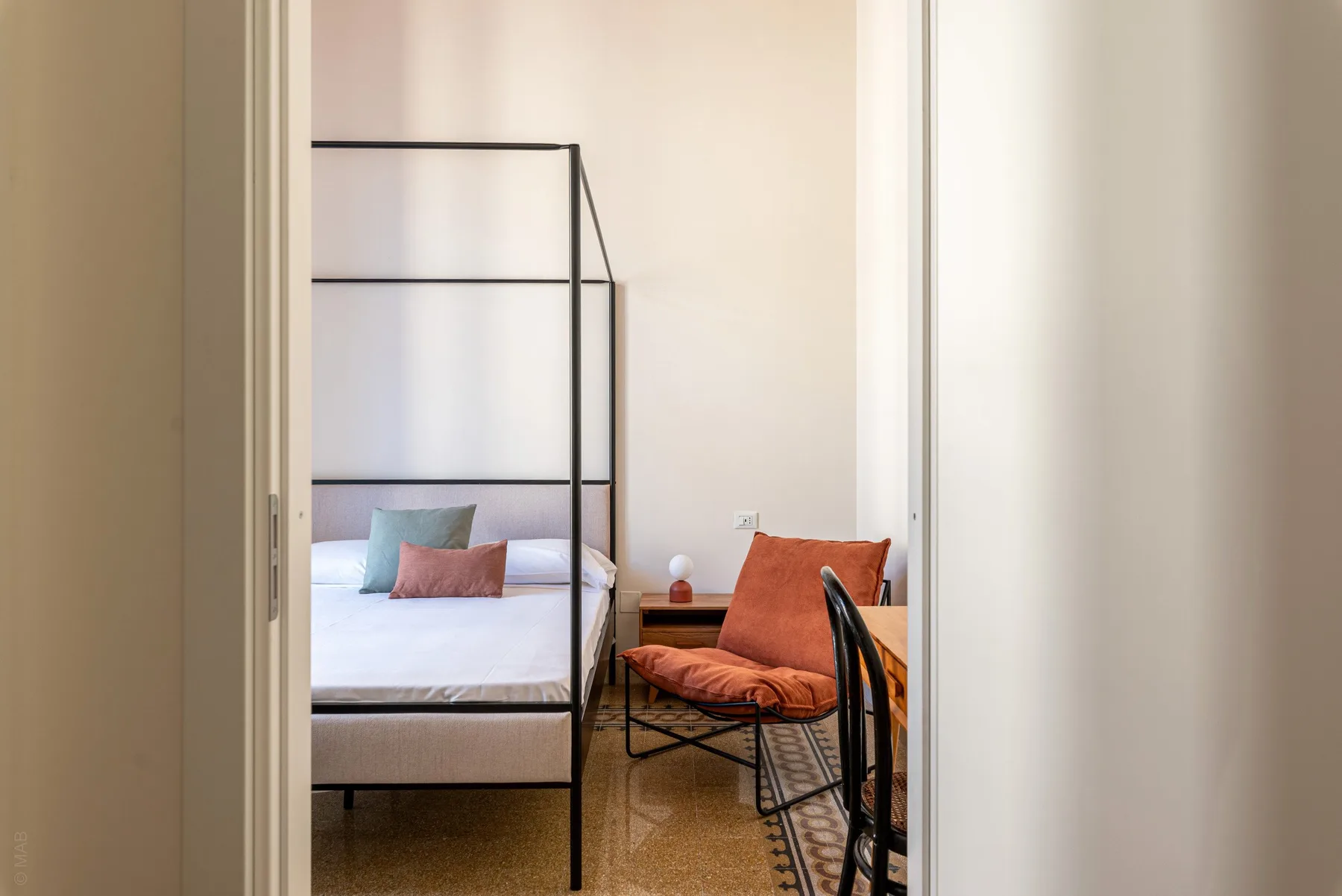 A bedroom with a black-framed bed and a small desk beside it.