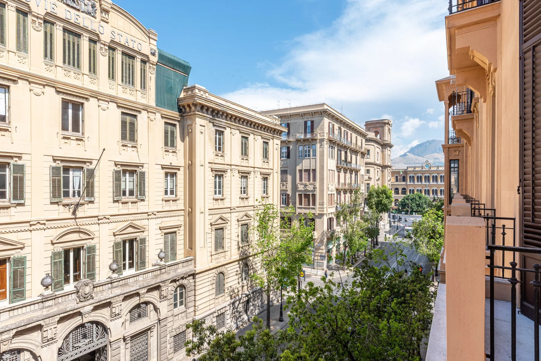 A city street lined with ornate multi-story buildings and trees.