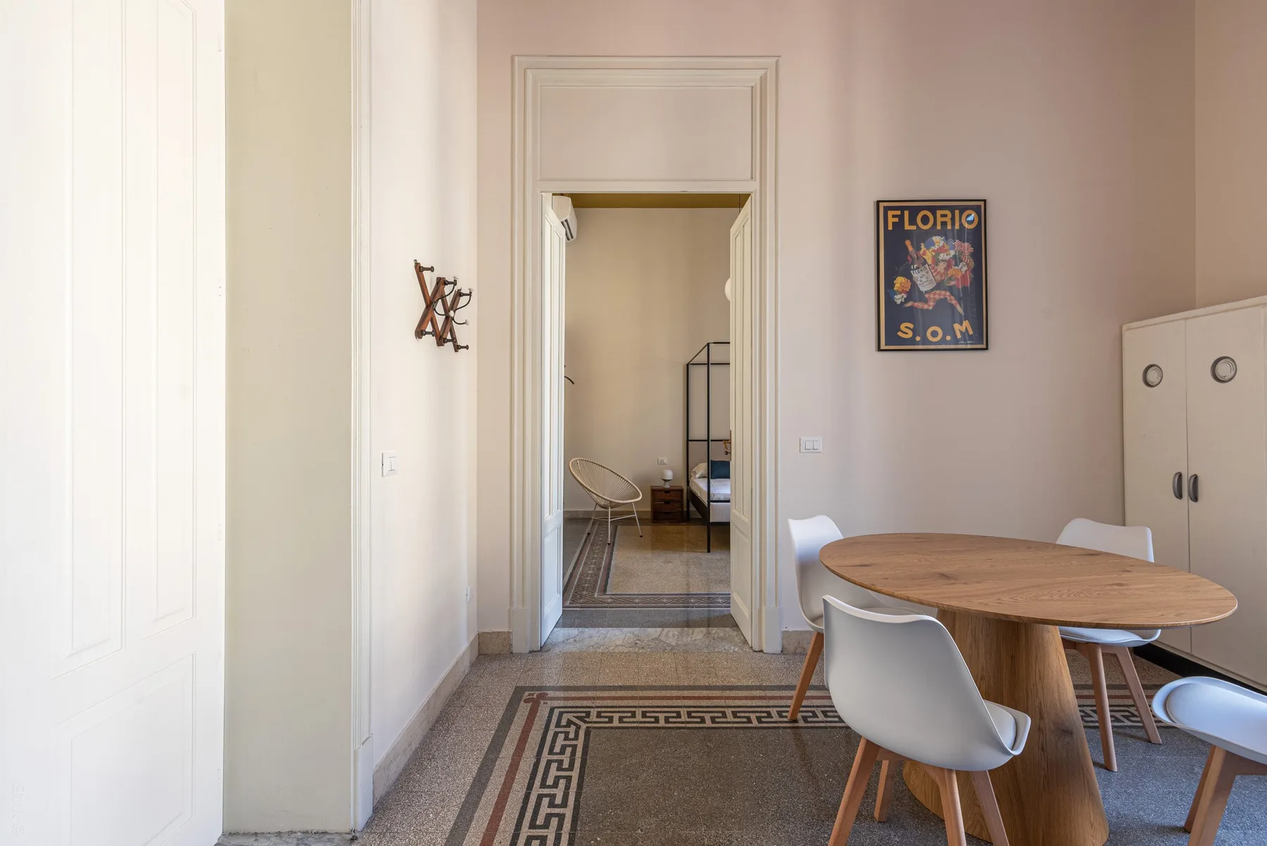 A dining area with a round table and chairs sits beside an open doorway.