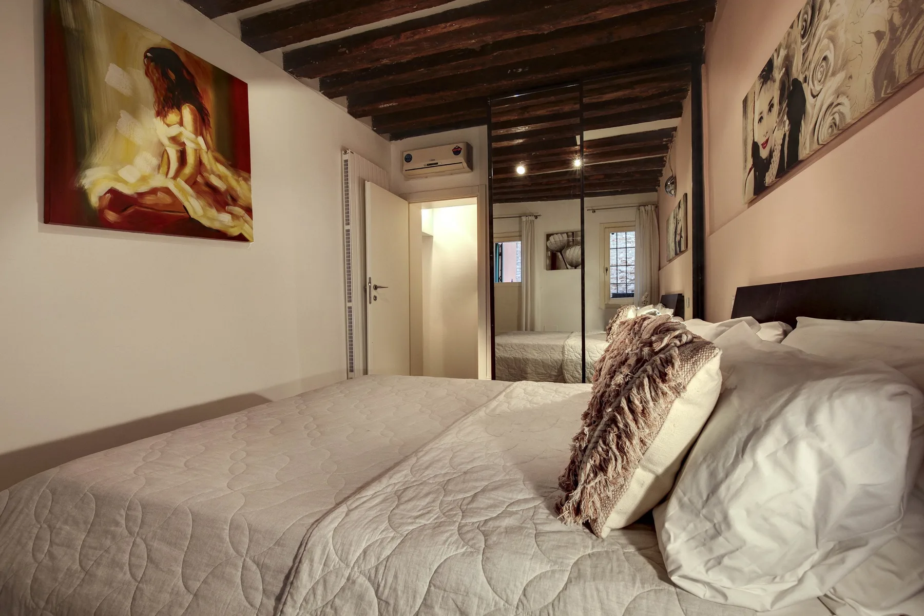 A bedroom with a large bed, decorative pillows, and artwork on the walls.