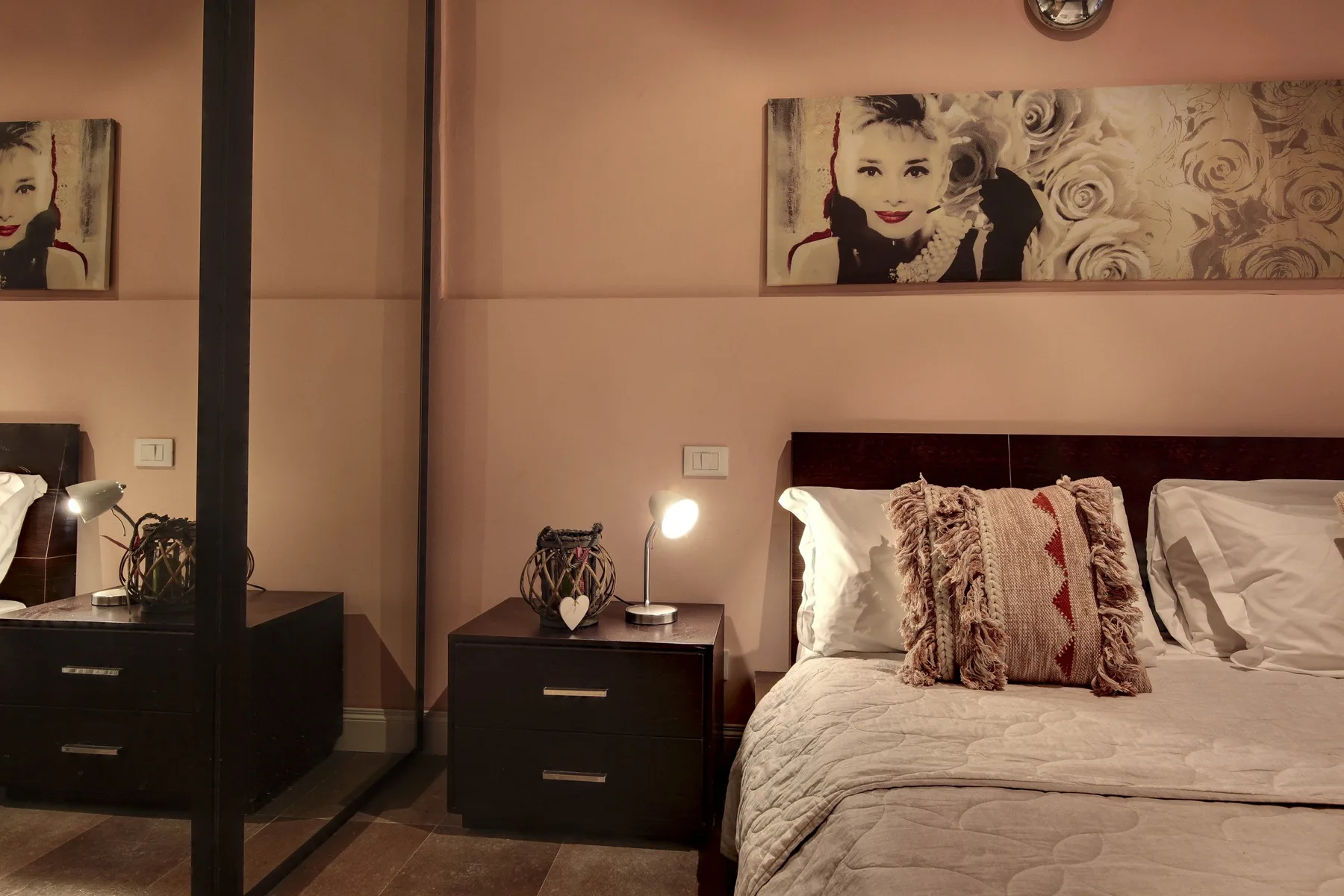 A bedroom with a neatly made bed, bedside table, and framed artwork above.